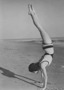 Woman handstands on beach